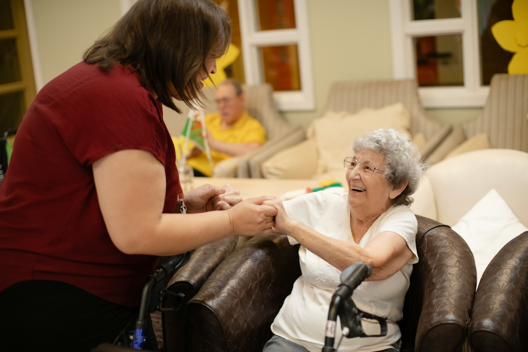 Older woman smiling while receiving support in a comfortable indoor setting.